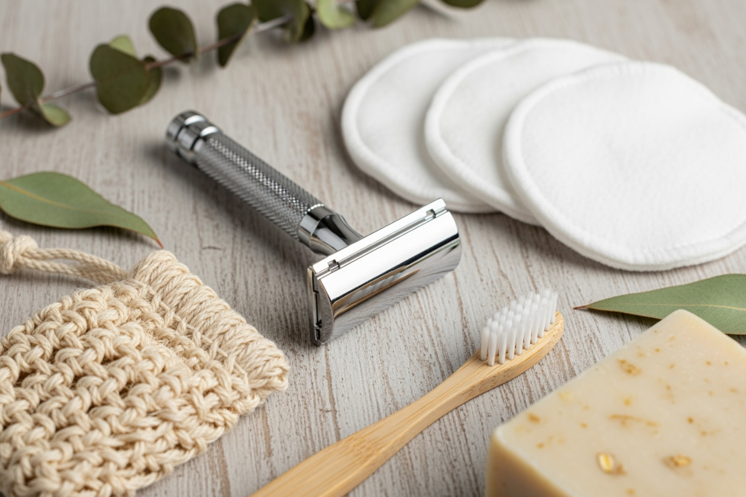 Zero-waste items like a safety razor, reusable cotton rounds, and a bamboo toothbrush arranged neatly - Zero-waste beauty routine