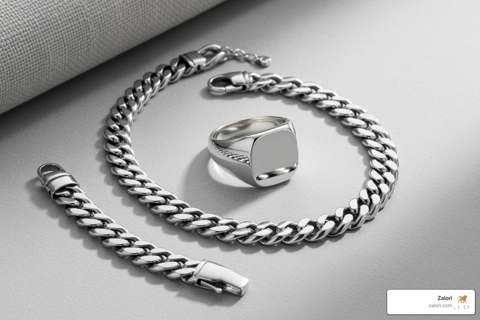 A flat lay showcasing a curated selection of men's luxury jewelry: a signet ring, a curb chain necklace, and a silver bracelet. - Luxury men's jewelry