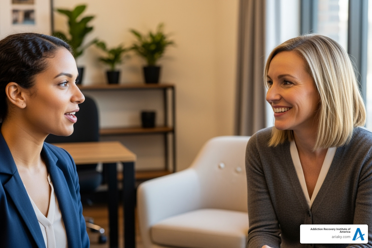 A woman speaking confidently with an intake counselor, both smiling and engaged in conversation in a warm, inviting office setting - rehab for women