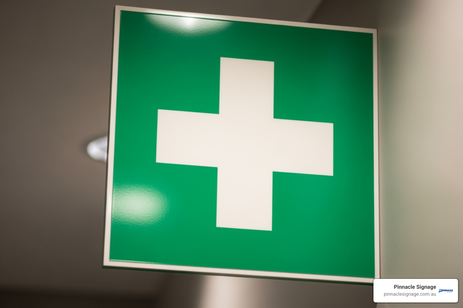 A universal first aid green sign with a white cross mounted on a wall for quick identification.