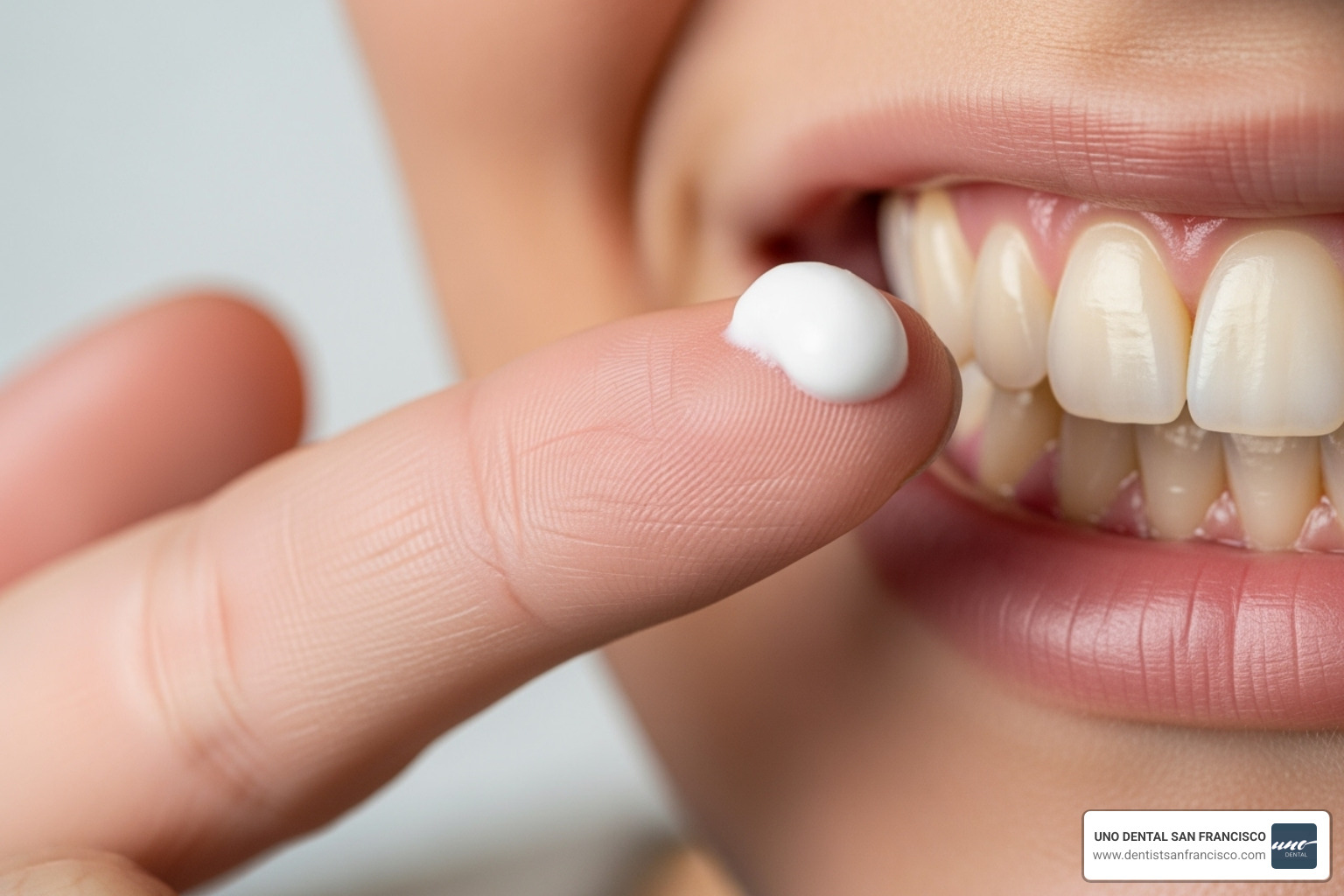 person applying desensitizing toothpaste to their finger to rub on a tooth - stop teeth sensitivity