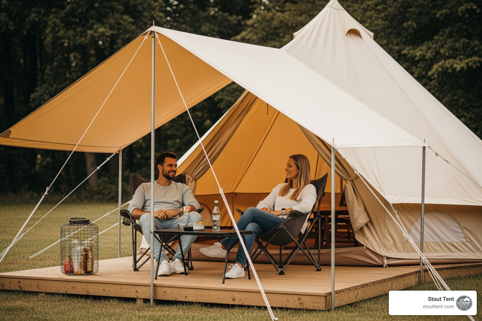 A classic canvas bell tent featuring a large, sturdy canvas awning extending from the front, under which a couple is relaxing on camping chairs with a small table, enjoying the outdoors. - Camping tent accessories