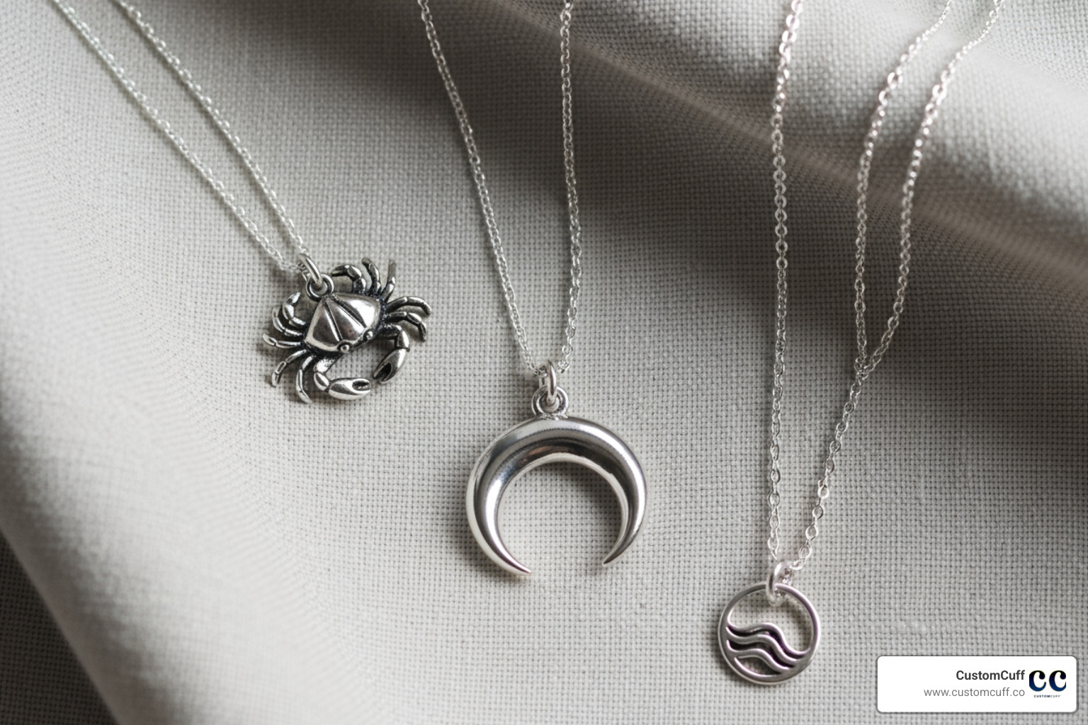 flat lay showing necklaces with crab, moon, and water-wave motifs - cancer zodiac sign necklace