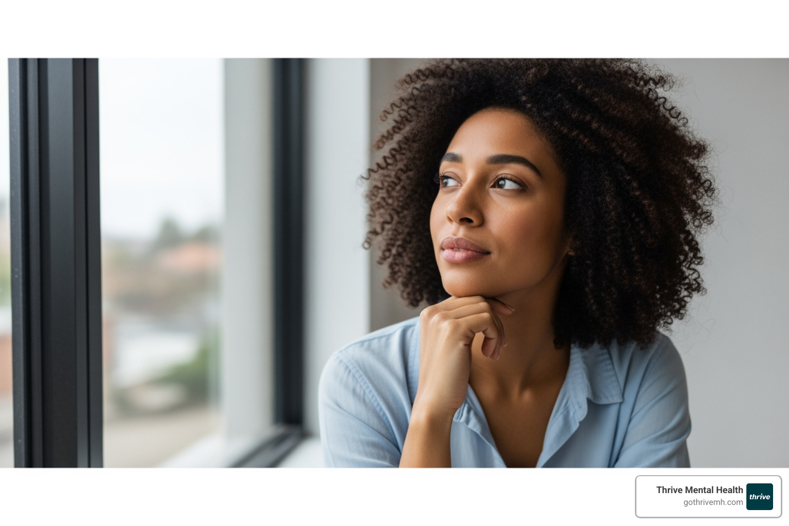 Young professional looking out window, considering outpatient mental health options. - outpatient mental health