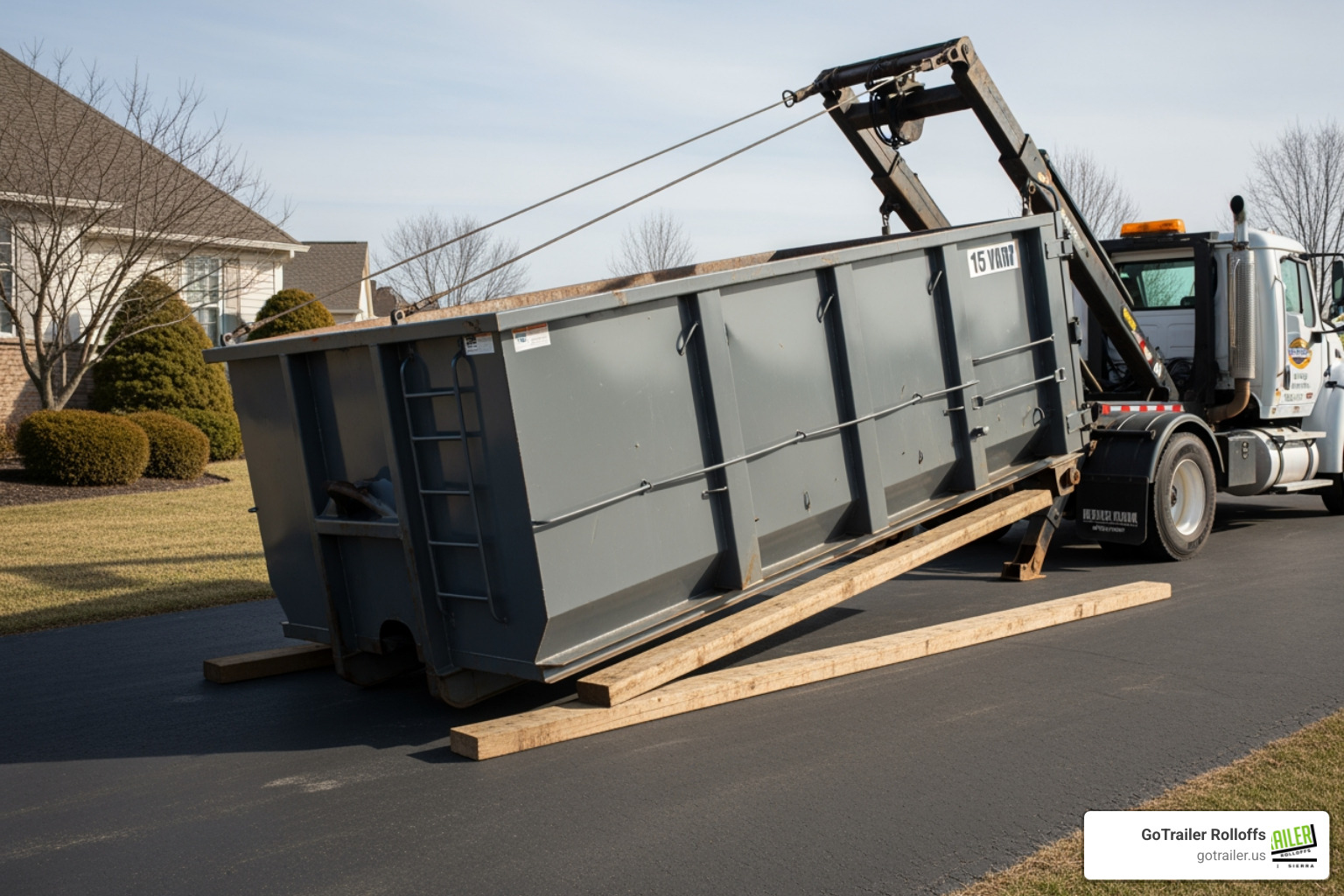 A 15-yard dumpster being carefully placed on wooden planks to protect a driveway - 15 yard roll off