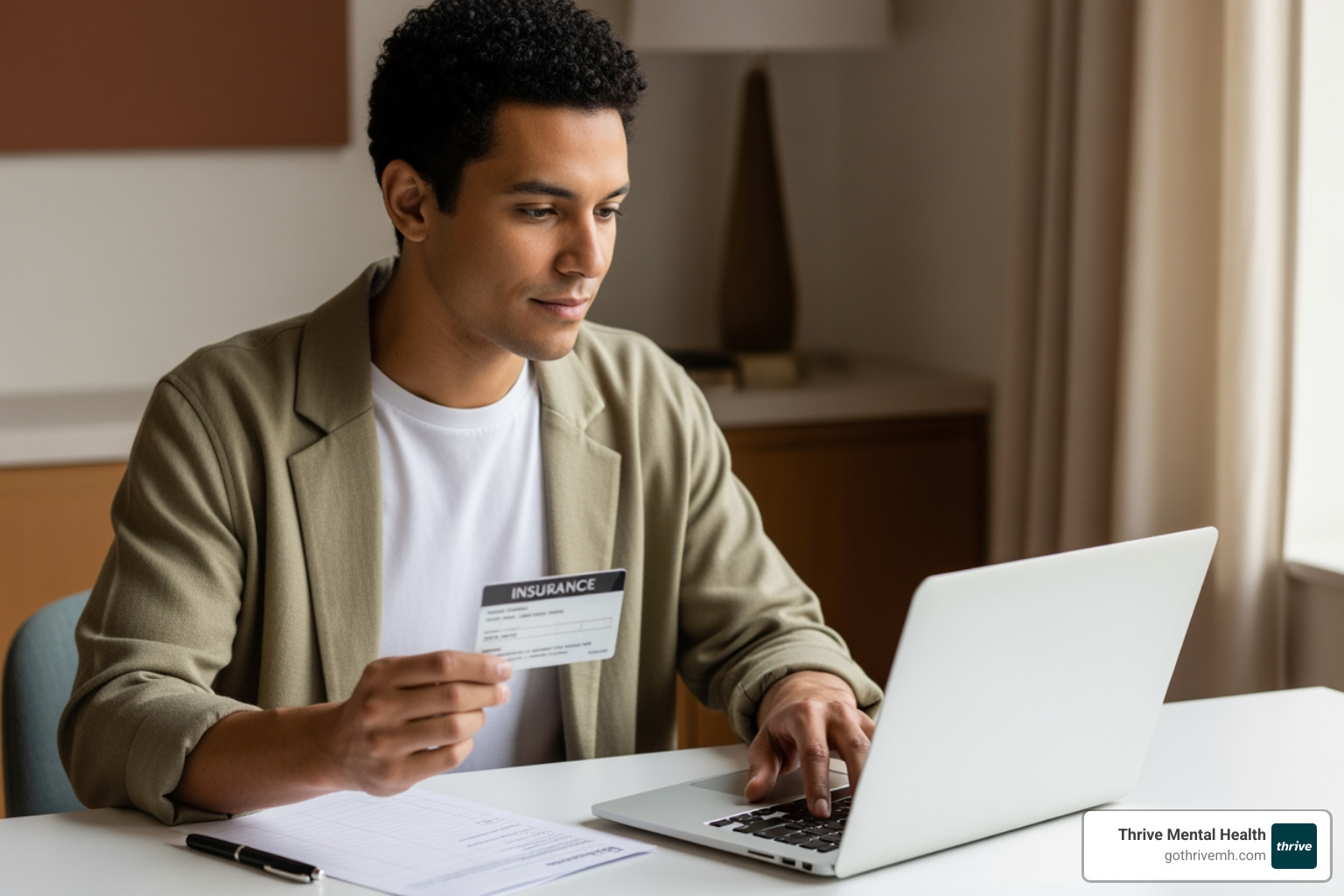 Person reviewing insurance card and laptop - I need to find a therapist in my city who specializes in trauma.