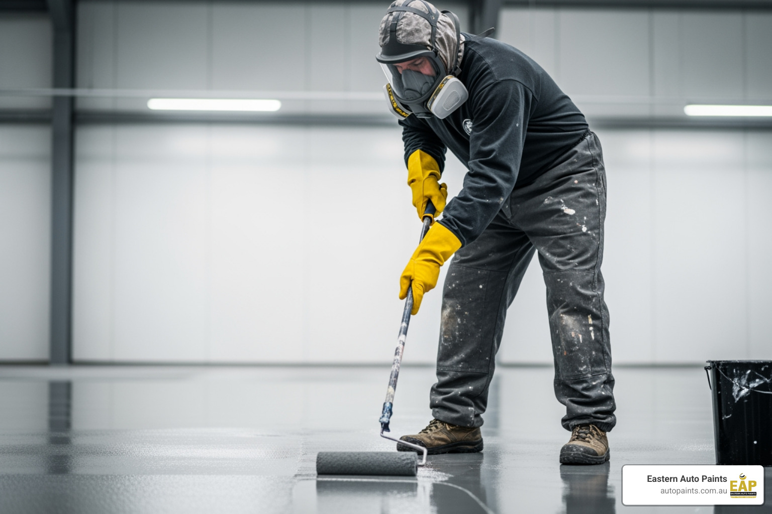 worker wearing full PPE, including respirator, gloves, and protective clothing, while applying epoxy floor paint in an industrial setting - industrial epoxy floor paint