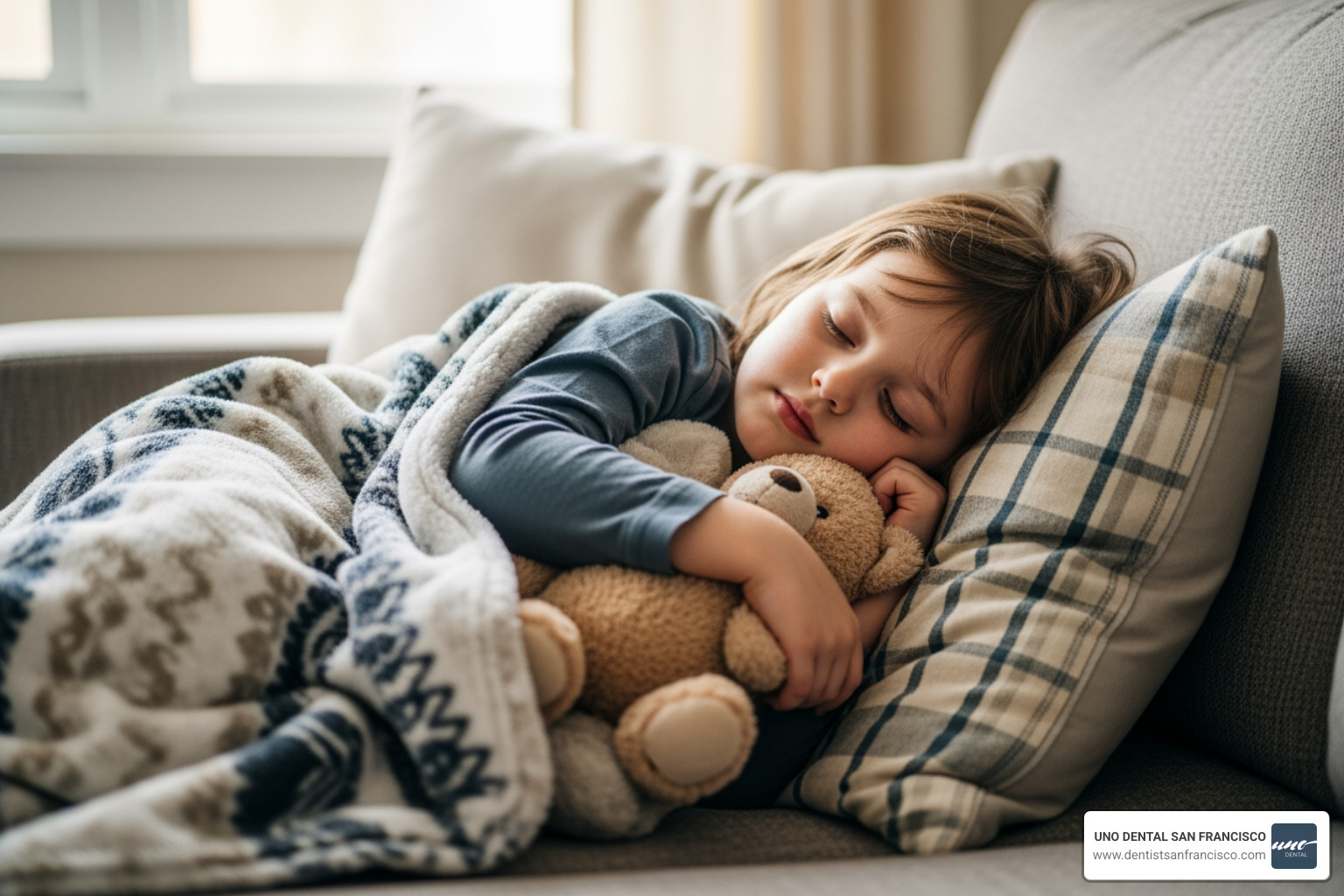 Child resting at home on a couch with a blanket and a stuffed animal, looking peaceful while recovering from a dental visit - child dental sedation Child resting at home on a couch with a blanket and a stuffed animal, looking peaceful while recovering from a dental visit - child dental sedation