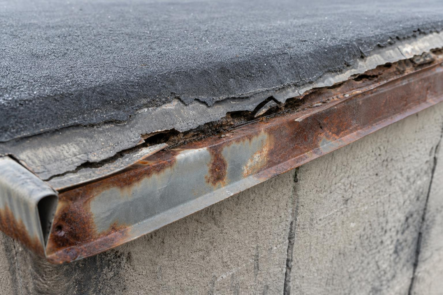 deteriorated drip edge on a flat roof showing membrane separation and rust deteriorated drip edge on a flat roof showing membrane separation and rust