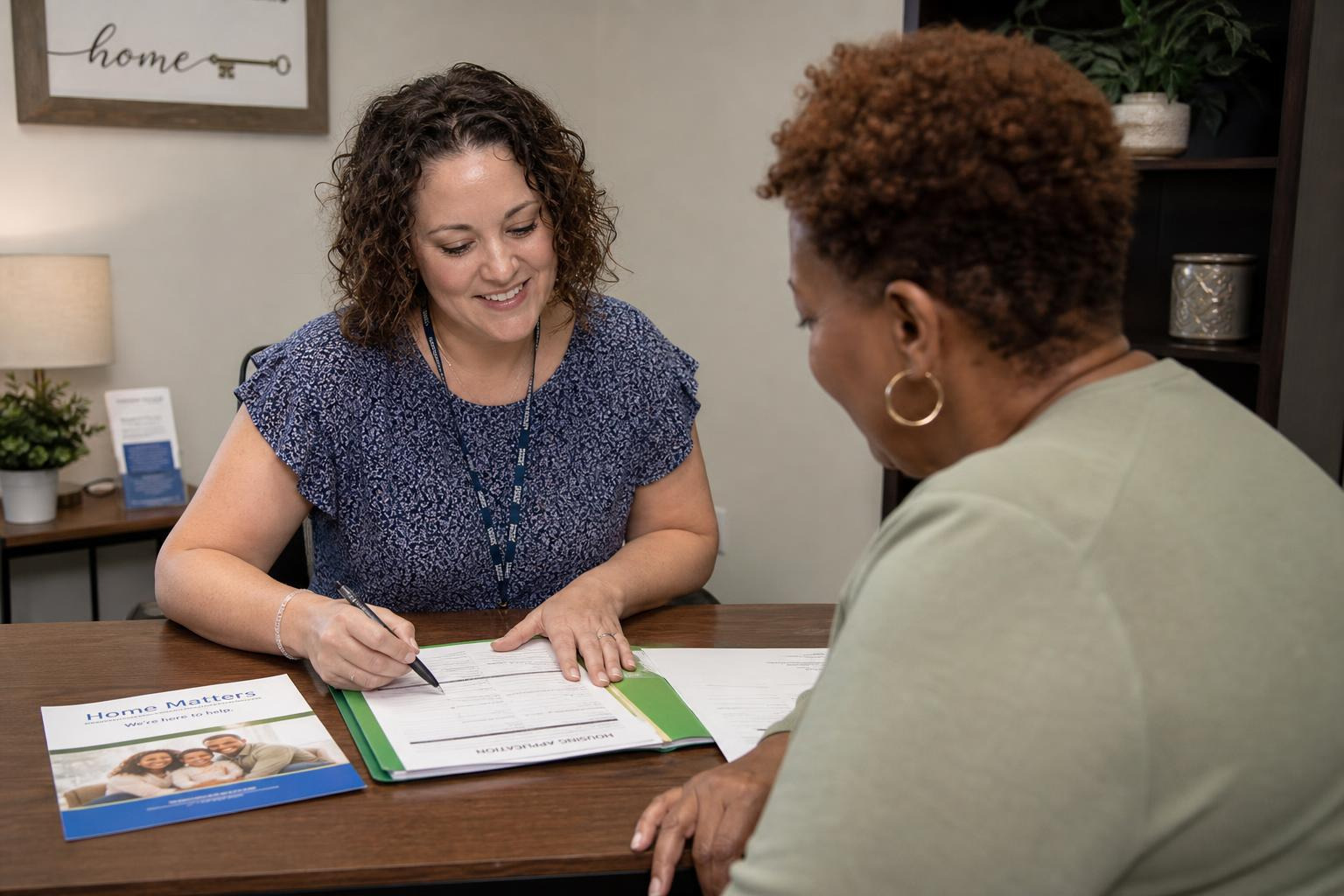 A friendly HUD-certified housing counselor sitting with a client, helping them fill out housing applications